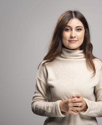 Portrait of a young woman posing on a gray wall . High quality photo